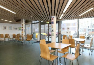 Spacious communal dining area with wooden tables and slatted ceiling.