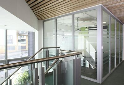 Glass-walled internal office pod with slatted wood ceiling.