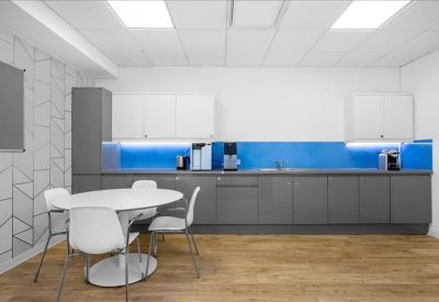 Modern communal kitchen with grey cabinetry and vibrant blue splashback.