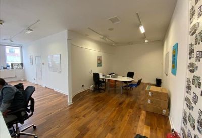 Open-plan workspace with polished wooden floors and a curved white feature wall.