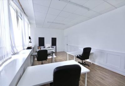 Bright private office suite featuring white desks and large windows with vertical blinds.