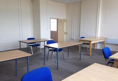 Spacious internal office suite with several desks and blue chairs.