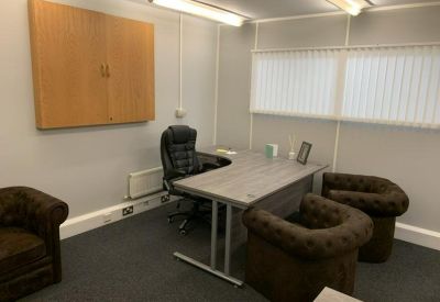 Executive office suite featuring a corner desk and tufted leather armchairs.