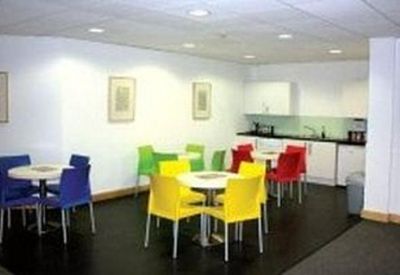 Bright communal kitchen and breakout area with colorful red, yellow, and blue chairs.