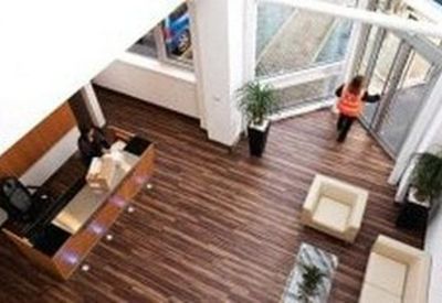 Aerial view of a modern reception area with wood floors, potted plants, and white armchairs.