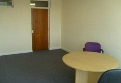 Small meeting room with a round wooden table and purple chair.