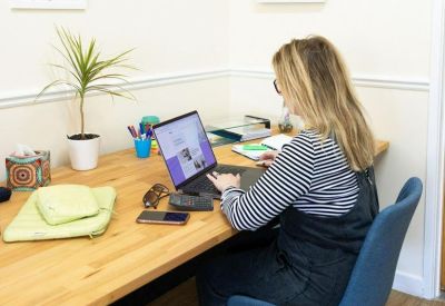 Individual workstation with a wooden desk, blue chair, and inspirational wall art.