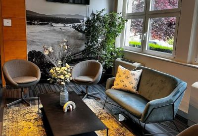 Spacious lounge area with modern sofa, coffee table, and large window overlooking greenery.