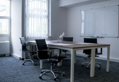 Modern meeting room with a wooden table, ergonomic chairs, and a whiteboard.