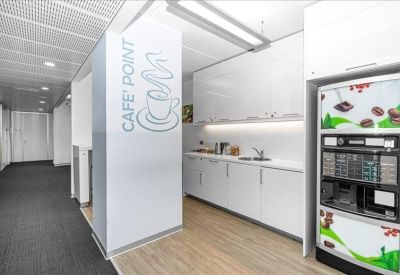 Clean, modern kitchen area with coffee station and white cabinetry.