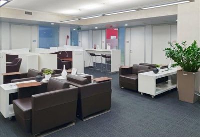 Co-working lounge with brown leather armchairs and white storage partitions.