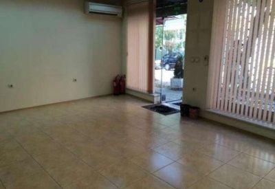 Bright vacant office space with polished tile flooring and large windows with blinds.