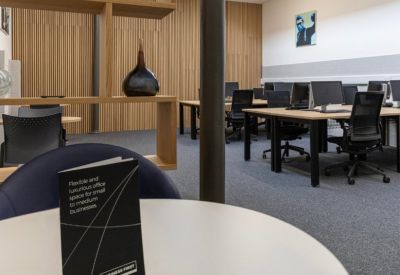 Modern coworking space with wooden desks and a decorative shelving unit.