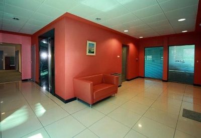 Modern reception lobby with vibrant red walls and polished tile flooring.