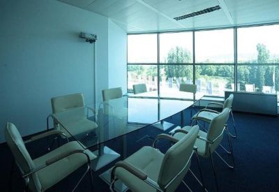 Sleek glass conference table with cream chairs in a sunlit meeting room.