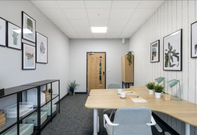 Modern communal desk area with white chairs, wooden tabletop, and various potted plants.