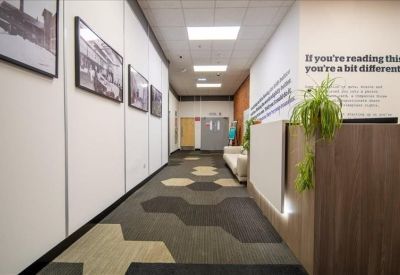 Modern reception area with a wooden desk, patterned carpet, and inspirational wall text.