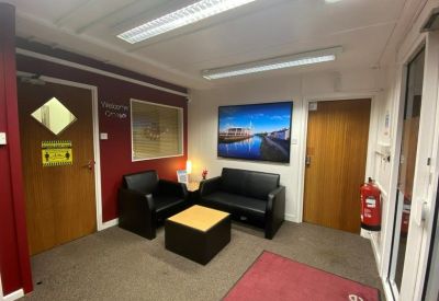 Small reception waiting area with black leather sofas and a warm wooden table.