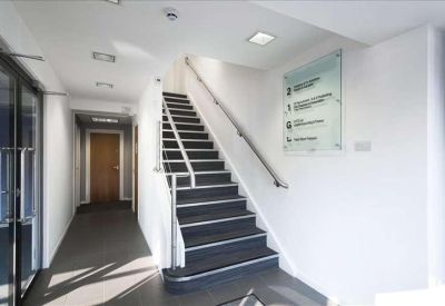 Modern internal staircase with dark treads, white walls, and an informational wall directory.