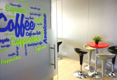 Vibrant break area with a red table, bar stools, and coffee-themed wall art.