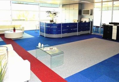Spacious reception area with blue carpets, white sofas, and a curved desk.