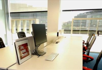 Bright workspace with white desks, ergonomic chairs, and large windows.