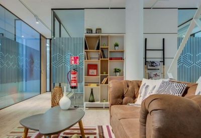 Modern lounge area with leather sofa, colorful rug, and decorative bookshelf.