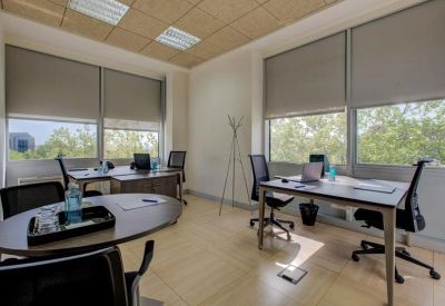 Bright office space with multiple workstations and large windows.