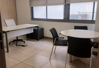 Private office featuring a large desk and a small round meeting table with black chairs.