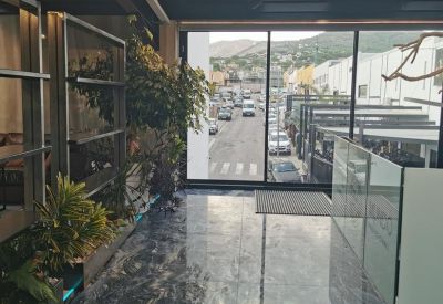 Glass-walled entrance hallway with polished stone flooring and street views.