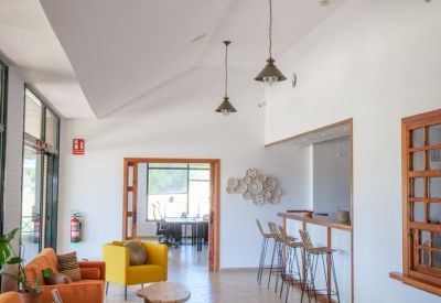 Bright lobby with orange and yellow sofas, wooden coffee tables, and bar area.
