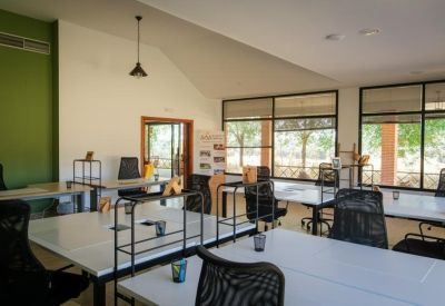 Bright open-plan office with multiple white desks and black mesh chairs.