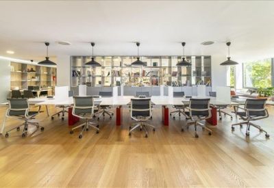 Bright coworking area with long white tables and stylish pendant lighting.