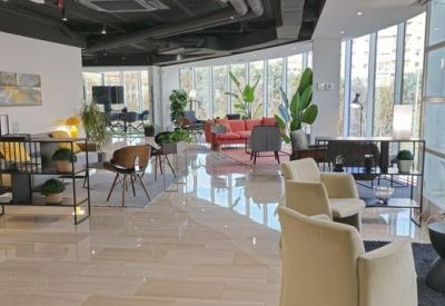 Spacious communal lounge with polished floors, modern armchairs, and floor-to-ceiling windows.