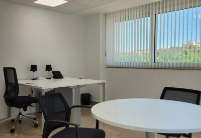 Small internal meeting room with a round white table and black ergonomic mesh chairs.