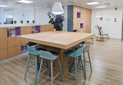 Breakout space with round white table and four black chairs by a large window.