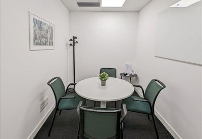 Small meeting room with round white table and green upholstered chairs.