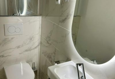 Modern minimalist bathroom with marble-style tiling and a sleek white vanity.