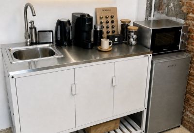 Kitchenette with a stainless steel counter, coffee station, microwave, and mini-fridge.