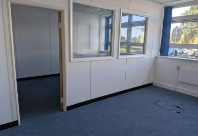 Small office room with two windows and blue carpet.