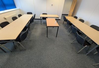 Meeting room with long tables and several chairs.