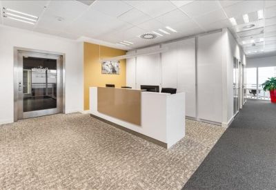 Professional reception area with a white and wood-toned desk and elevator access.