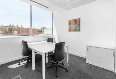 Private office suite featuring a white desk, black chairs, and framed wall art.