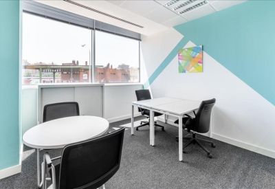Small meeting room with white tables and a blue geometric feature wall.