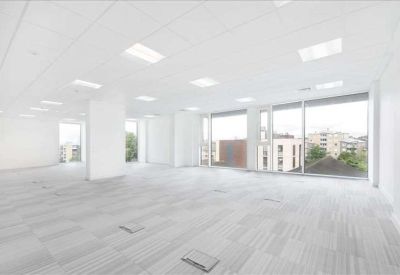 Bright vacant workspace featuring acoustic ceiling tiles and large windows for natural light.