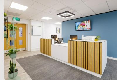 Bright reception area with a wood-slat front desk and a blue feature wall.