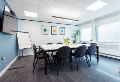 Professional meeting room with a large white table, black chairs, and a whiteboard.