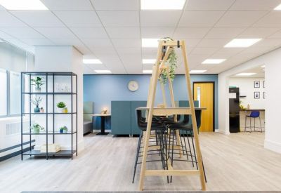 Bright coworking lounge with wooden high-top seating and a blue accent wall.