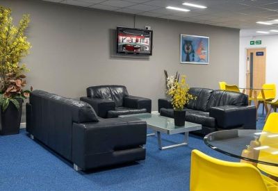 Modern communal lounge area with black leather sofas and bright yellow chairs.