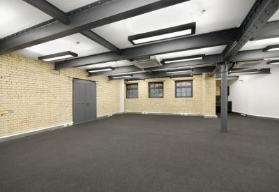 Industrial-style open-plan office space with exposed ceiling beams and brick walls.